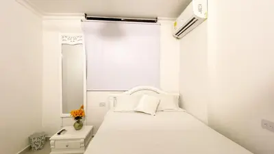 a white bedroom with a bed and a window at Apartamento Coveñas in Coveñas