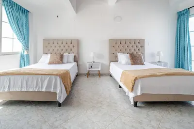 two beds in a white room with blue curtains at Luxury House Perfect Location in Cartagena de Indias