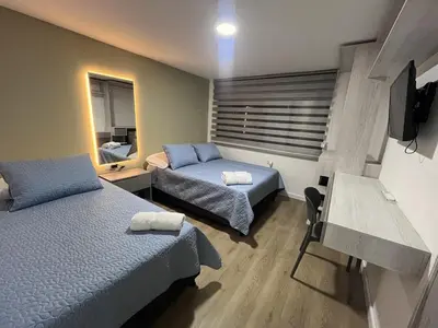 a bedroom with two beds and a desk and a television at Loft Deluxe - Nuevo, Acogedor, Integral, Ubicación inmejorable in Barranquilla