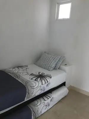 a bed in a white room with a pillow on it at Morros Suites Apartamentos in Cartagena de Indias