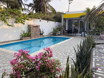 a swimming pool with flowers in front of a house at Cabaña Julianita in Santa Veronica