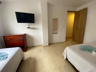 a bedroom with two beds and a tv on the wall at Hotel Prado Cartagena in Cartagena de Indias