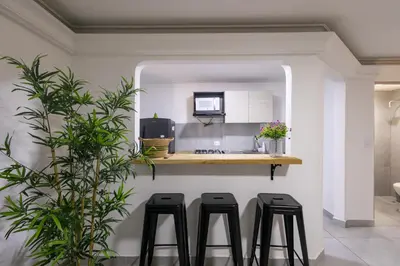 a kitchen with three black stools on a counter at Cozy apartment in bocagrande in Cartagena de Indias