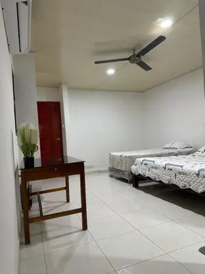 a room with two beds and a table and a ceiling fan at Habitación en Santiago de Tolú in Santiago