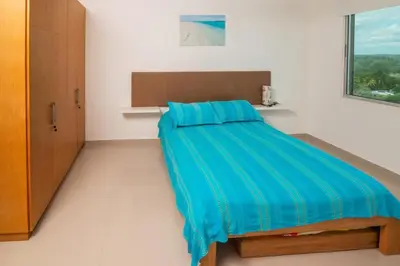 a bedroom with a bed with a blue blanket on it at Hermoso Apartamento Frente al Mar 3 Habitaciones B62 in Coveñitas