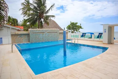 a blue swimming pool with a view of the ocean at Hermoso Apartamento Frente al Mar 3 Habitaciones B62 in Coveñitas