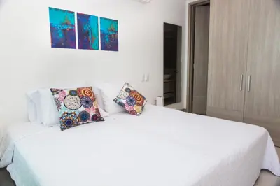 a white bed with pillows on it in a bedroom at Palmetto Sunset in Cartagena de Indias