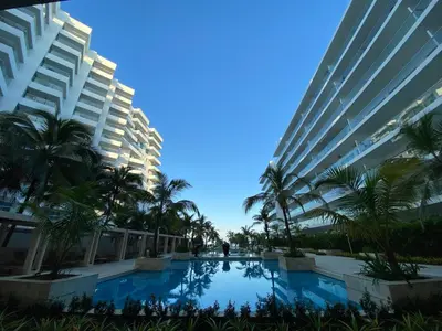 a swimming pool between two tall buildings with palm trees at Elegante Apartamento en Cartagena con salida al Mar, Morros Epic in Cartagena de Indias