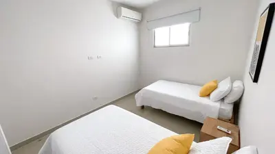 a white room with two beds and a window at Magico Apartamento Frente al Mar 4 Habitaciones BM43 in Coveñitas