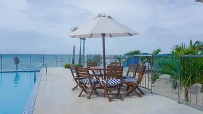 a table and chairs with an umbrella next to a swimming pool at Magico Apartamento Frente al Mar 4 Habitaciones BM43 in Coveñitas