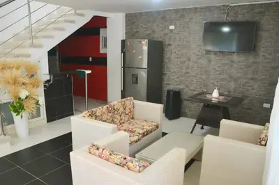 a living room with white chairs and a refrigerator at Cabaña AveMaria in Coveñas