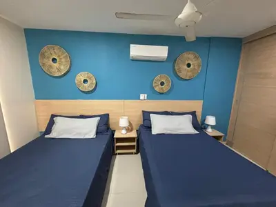 two beds in a room with blue walls and clocks at Refugio junto al mar en el Cabrero in Cartagena de Indias