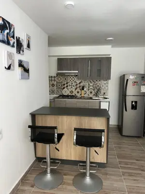 a kitchen with two bar stools and a refrigerator at Apartamento en Barranquilla in Puerto Colombia