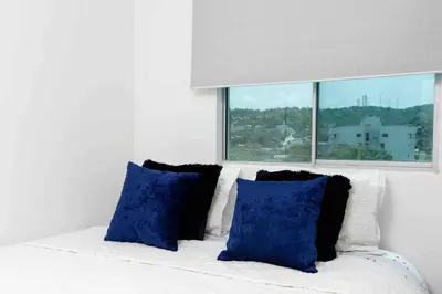 a white couch with blue pillows and a window at Luxury CTG Condo Near Beach Cold AC & Hot Water in Cartagena de Indias