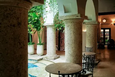 a room with columns and tables and potted plants at Hotel Boutique Patio Corao in Cartagena de Indias