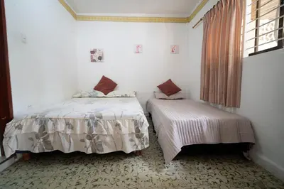 two beds in a white room with a window at Casa Caribe, excellent location in Bocagrande in Cartagena de Indias