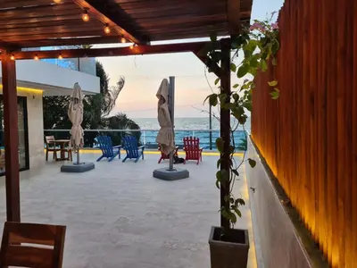 a patio with chairs and umbrellas and the ocean at Camino Palmero Coveñas in Coveñas