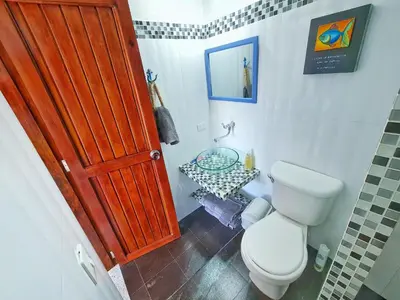 a bathroom with a toilet and a wooden door at Lujosa cabana con piscina playa y servicio in San Silvestre