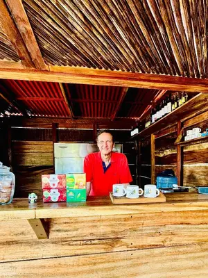 a man is standing behind a counter with cups at Aquarius Diving Club y Cabañas in Rincón
