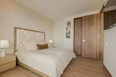a bedroom with a large white bed and a wooden cabinet at Vista al Mar/ Centro Histórico/ Nuevo Piso 26 1BR in Cartagena de Indias