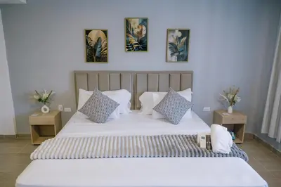 a bedroom with a large white bed with three pictures on the wall at Davé Paradise in Cartagena de Indias