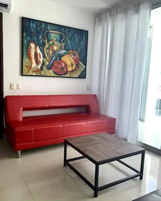 a red couch in a living room with a painting at Morros Vitri Disfruta de acceso directo a la playa in Cartagena de Indias