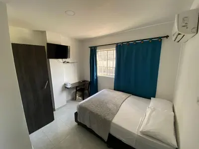 a bedroom with a bed and a blue curtain at Hotel Villa Marta Cartagena in Cartagena de Indias