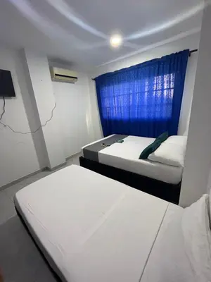 a bedroom with two beds and a blue window at Hotel Villa Marta Cartagena in Cartagena de Indias