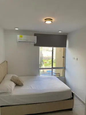 a bedroom with a white bed with a window at Apartamento acogedor in Barranquilla