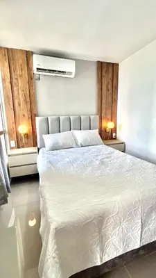 a bedroom with a large white bed with two lamps at Encanto cerca al mar in Cartagena de Indias
