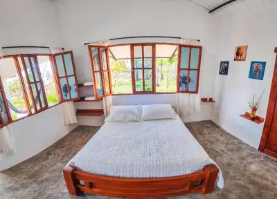 a bedroom with a bed in a room with windows at Casa Blanca Broqueles Hotel in Moñitos
