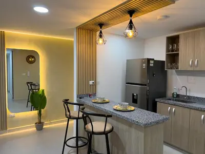 a kitchen with a counter with stools and a refrigerator at Cozy and close to the airport in Cartagena de Indias