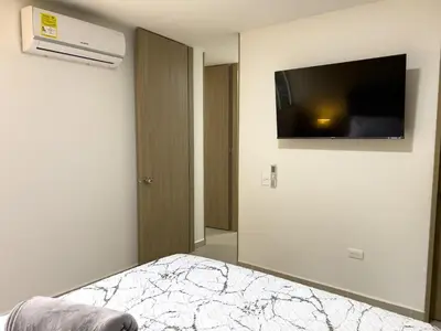 a bedroom with a bed with a television on the wall at Cozy and close to the airport in Cartagena de Indias