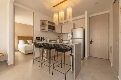 a kitchen with a bar with stools and a refrigerator at Apartment with a Pool and Parking 2Bed in Cartagen in Cartagena de Indias