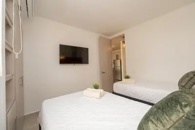 a bedroom with two beds and a tv on the wall at Apartment with a Pool and Parking 2Bed in Cartagen in Cartagena de Indias