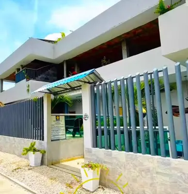 a white house with a gate and a building at Escapada Perfecta en Apartasuites Privadas Coveñas in Coveñas