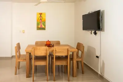 a dining room table with chairs and a flat screen tv at Magico Apartamento Frente al Mar 2 Habitaciones B11B in Coveñitas