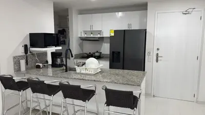 a kitchen with a counter with bar stools and a black refrigerator at ESPECTACULAR APARTAMENTO MORROS 3 Acceso directo a la Playa!!! in Cartagena de Indias