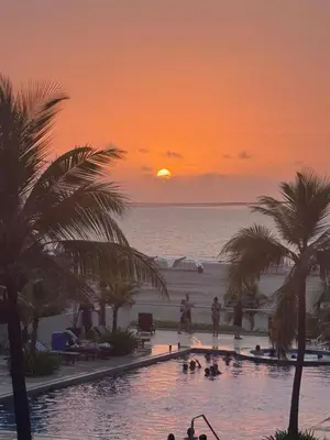 a sunset over the ocean with a swimming pool with palm trees at ESPECTACULAR APARTAMENTO MORROS 3 Acceso directo a la Playa!!! in Cartagena de Indias