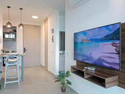a living room with a large flat screen tv on a wall at Moderno, vista al mar, AC, Wifi200MB,5Min Aeropuerto in Estación El Salto