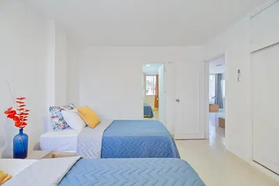 two beds in a white room with a blue vase at Hermoso apartamento en manga piso 3 in Cartagena de Indias