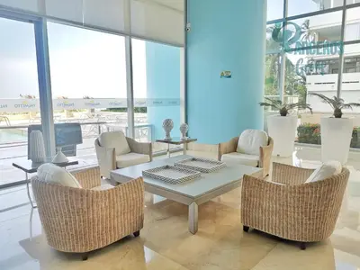 a living room with a table and chairs and windows at Apartamentos Palmetto Sunset por Parceros Group in Cartagena de Indias