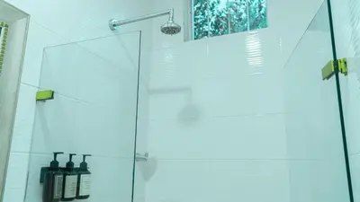 a bathroom with a glass shower with bottles on a shelf at Casa Niza - Colonial house in Cartagena de Indias
