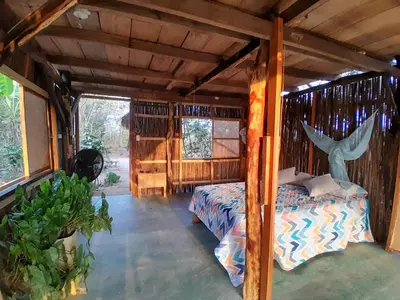 a bedroom with a bed in a wooden house at Casa Surya - Cabaña sostenible en la naturaleza in San Onofre