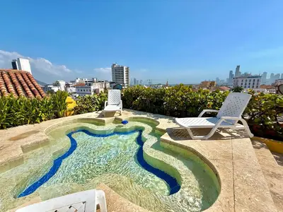 a swimming pool on top of a building with two chairs at by Calamari Homes - El Porvenir 306 walled city in Cartagena de Indias