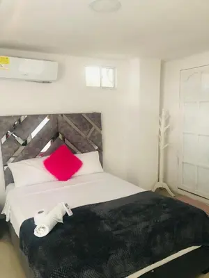 a bedroom with a large bed with a red pillow at Hotel Altos del Prado in Barranquilla