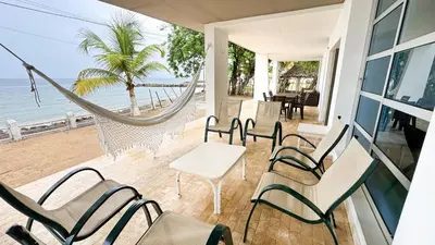 a porch with chairs and a hammock on the beach at Cabaña Costa de Oro in San Antero