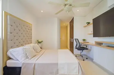 a bedroom with a bed with a ceiling fan and a chair at Bocagrande Excelente Ubicacion Apto CONFORT con una gran vista al MAR y PLAYAS in Cartagena de Indias
