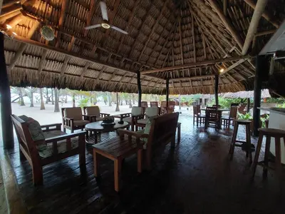 a restaurant with tables and chairs under a straw umbrella at Cabaña frente al mar en la playa del Calao in San Antero