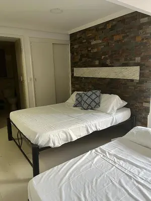two beds in a room with a brick wall at Lindo Apartstudio en El Laguito in Cartagena de Indias